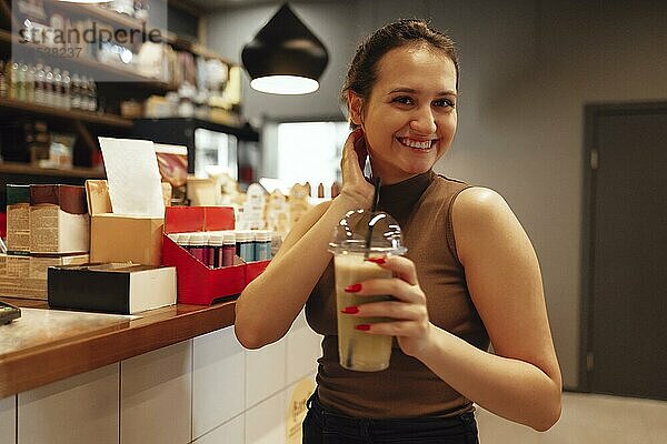 Glückliches junges weißes Mädchen trinkt Smoothies in einem stilvollen Cafe im Innenbereich. Lächelnd positive weibliche hält Cocktail mit einem Strohhalm im Restaurant. Raum kopieren