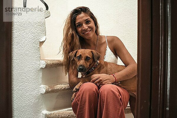 Porträt von Beautiful Latina Frau umarmt ihren Hund beide Blick in die Kamera. Liebe für Tiere