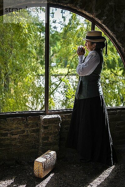 Profilbild einer traditionell gekleideten Latina  die nachdenklich durch das Fenster schaut