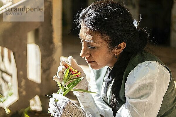 Porträt einer Latina  die im Freien sitzt und an Blumen riecht