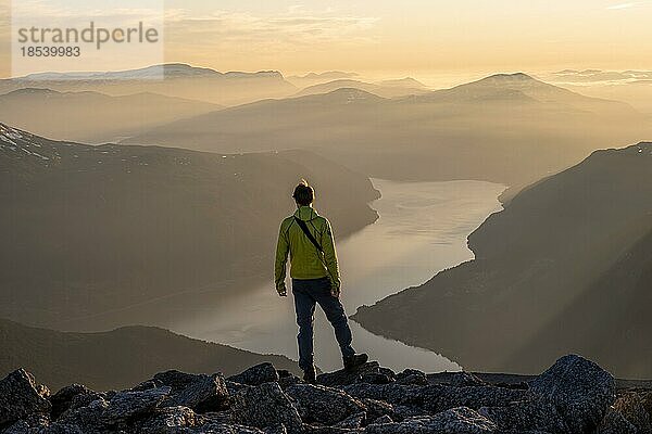 Wanderer auf dem Gipfel des Skåla  Ausblick auf Berge und Fjord Faleidfjorden  bei Sonnenuntergang  Loen  Norwegen  Europa