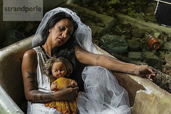 Verwirrte Braut mit einer Puppe in einer Badewanne. Inspiriert von der traditionellen amerikanischen Legende von la llorona (der weinenden Frau)