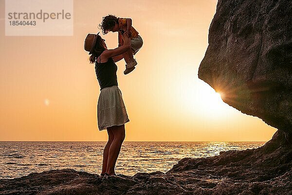 Silhouette von Mutter und Sohn  die Spaß haben  den Sohn in den Sonnenuntergang am Strand von Tacoron auf El Hierro  Kanarische Inseln  Urlaub Konzept  orange Sonnenuntergang