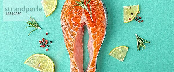 Ungekochte rohen frischen Fisch Lachssteak Draufsicht auf blauem Hintergrund mit Rosmarin  Zitrone Keile und Gewürze  Delikatesse gesunden Fisch Kochen und Ernährung Konzept flach legen