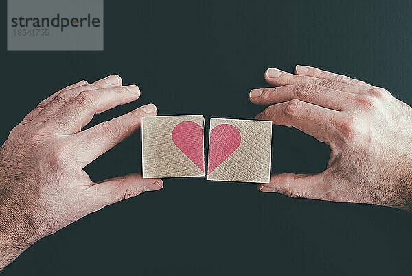 Hände  die Holzklötze mit rotem Herz  Liebe oder gebrochenem Herz verbinden oder trennen
