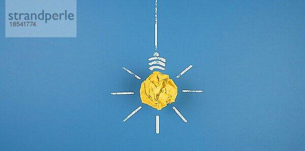 Glühbirne aus zerknülltem gelben Papier auf blauem Hintergrund  Idee und Innovationskonzept