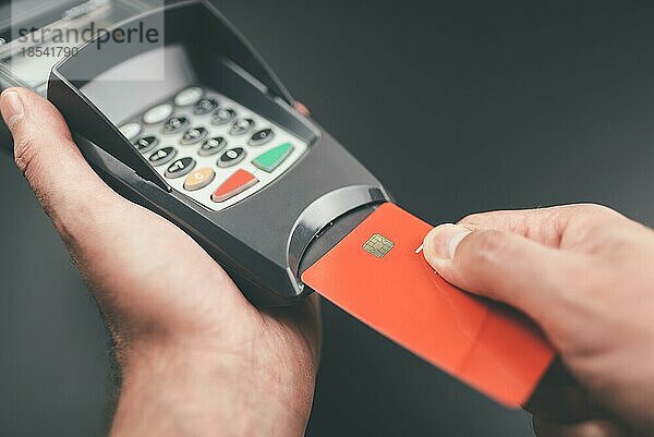 Person steckt Kreditkarte oder Debitkarte in POS-Zahlungsterminal oder Kreditkartenleser