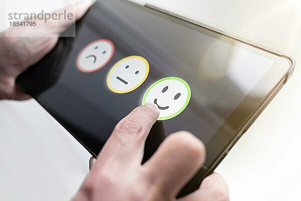 Zufriedene Person  die ein positives Feedback gibt  indem sie ein Smiley-Gesicht auf dem Touchscreen eines digitalen Tablets berührt  Konzept zur Bewertung der Dienstleistungsqualität