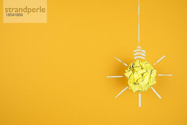 Glühbirne aus zerknülltem gelben Papier auf orangem Hintergrund  Idee und Innovationskonzept