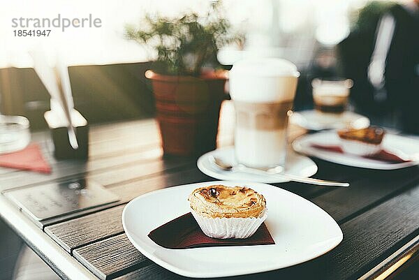 Portugiesisches gebäck pastel de nata auf holztisch mit heißem kaffee getränk