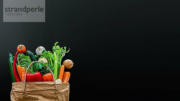 Draufsicht auf frisches Bio-Gemüse  das auf dem Wochenmarkt in einer braunen Papiertüte gekauft wurde  vor dunklem Tisch-Hintergrund