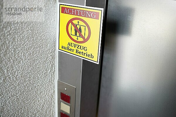 Gelbes Serviceschild mit deutschem Text für AUFZUG AUSSER BETRIEB an der Aufzugstür  digitales Composite
