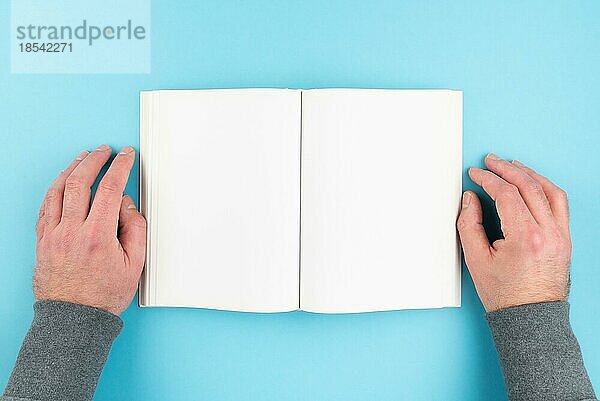 Blick von oben auf eine Person  die ein Buch liest und die Hände auf beide Seiten legt  leere Seite eines gebundenen Buches mit Kopierbereich