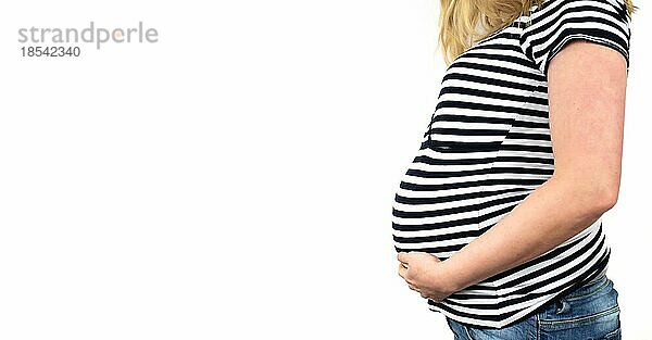 Seitenansicht des Mittelteils einer im 9. Monat schwangeren Frau in gestreiftem Top und Jeans mit Händen auf dem Bauch vor weißem Hintergrund
