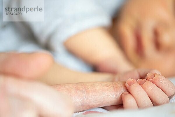 Nahaufnahme eines neugeborenen Jungen  der den Finger eines Elternteils hält