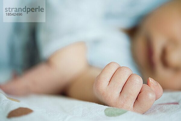 Nahaufnahme der Hand eines neugeborenen Babys  das auf dem Bett liegt