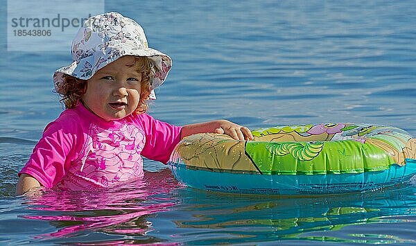 Kleinkind spielt mit Schwimmring im Wasser