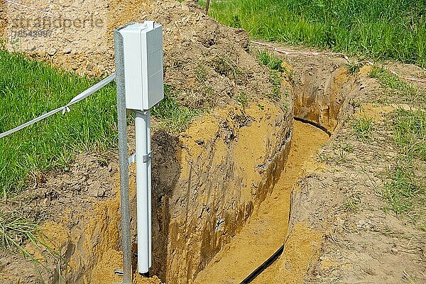 Offener Kabelgraben mit Stromkabel und Hausanschlusskasten