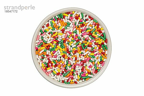 Draufsicht auf bunte Regenbogen Zuckerstreusel in weißen Keramik-Tasse auf weißem Hintergrund mit Clipping-Pfad