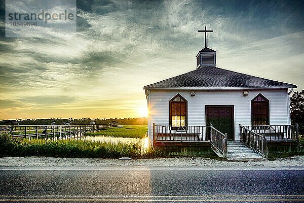 Pawleys Island  Pawleys Island Kapelle  Kapelle  Kirche  South Carolina  auf dem Wasser  Sumpf  Religion  Anbetung  Gottesdienst  beten  Wahrzeichen  historisch  Sumpfgras  Bucht  Barriereinsel  Wasser  Gezeitenwasser  Sonnenuntergang  gelb  warm  Fenster  beleuchtet  Abend  Dämmerung  Straße  Sand  Gräser  bewölkter Himmel  Wolken  orange  Fensterladen  Tür  Glockenturm  Kreuz  klein  Stufen  Küste  idyllisch  heiter  landschaftlich  Kulisse