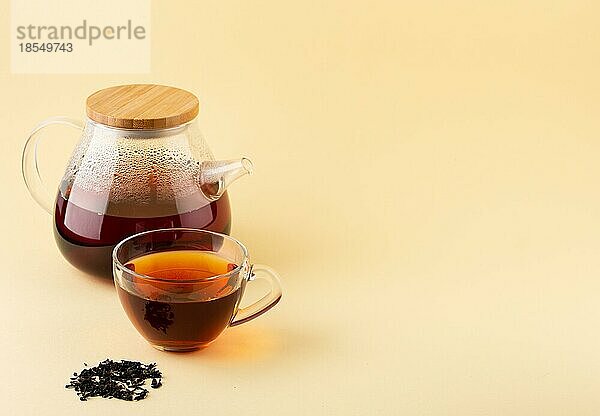 Frisch gebrühter BioSchwarztee in transparenter Glasteekanne und in glasklarer Teetasse auf beigem Hintergrund  selektiver Fokus. Tee mit Platz für Text