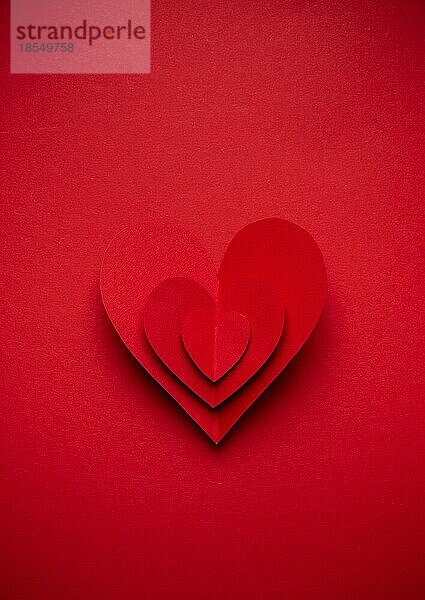 Großes voluminöses rotes Herz aus Papier auf rotem monochromen Hintergrund geschnitten  Papierhandwerk OrigamiStil von oben. Romantische Valentinstag Symbol  Liebe Konzept. Papier Kunst Design  14. Februar Feier