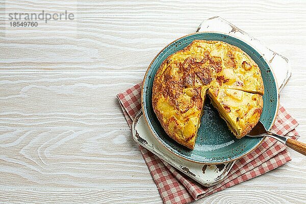 Hausgemachte spanische Tortilla mit einer Scheibe geschnitten Omelett mit Kartoffeln auf einem Teller auf weißem Holz rustikalen Hintergrund Draufsicht. Traditionelles Gericht von Spanien Tortilla de patatas für Mittagessen oder Snack  Kopie Raum