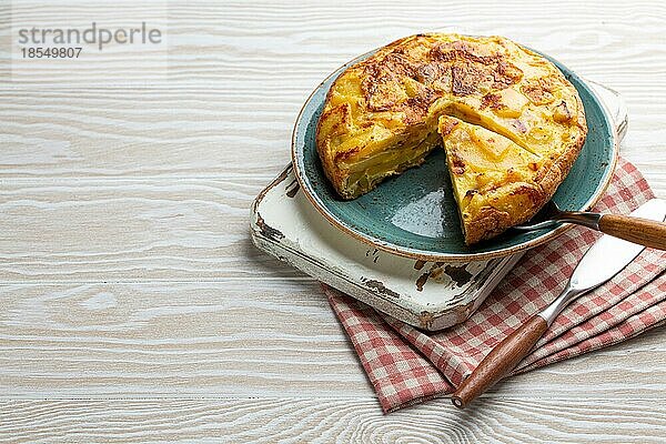 Hausgemachte spanische Tortilla mit einer Scheibe geschnitten Omelett mit Kartoffeln auf einem Teller auf weißem Holz rustikalen Hintergrund Draufsicht. Traditionelles Gericht von Spanien Tortilla de patatas für Mittagessen oder Snack  Kopie Raum