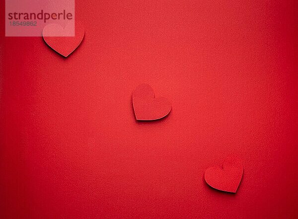 Drei rote Herzen in einer Reihe aus Papier auf rotem Hintergrund geschnitten  Handwerk OrigamiStil von oben. Romantische Valentinstag rot monochrome Liebe Konzept. Unterschiedliche Größe Herzen Draufsicht  Papier Kunst Design
