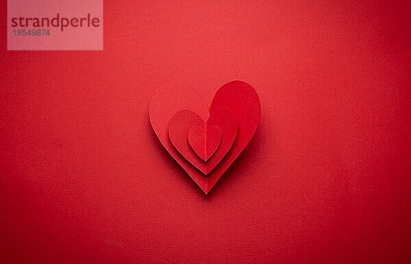 Großes voluminöses rotes Herz aus Papier auf rotem monochromen Hintergrund geschnitten  Papierhandwerk OrigamiStil von oben. Romantische Valentinstag Symbol  Liebe Konzept. Papier Kunst Design  14. Februar Feier