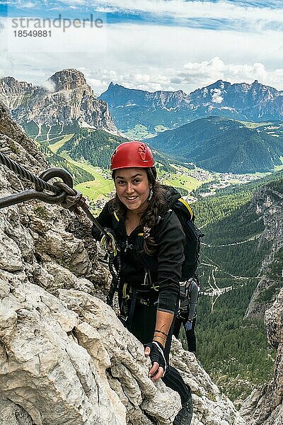 Junge attraktive Bergsteigerin auf einem schwierigen Klettersteig in den Dolomiten in Alta Badia in Südtirol in Italien