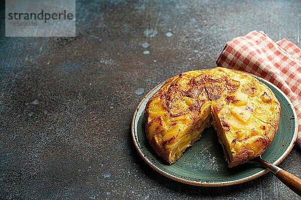 Hausgemachte spanische Tortilla mit einer Scheibe geschnitten Omelett mit Kartoffeln auf einem Teller auf Stein rustikalen Hintergrund Draufsicht. Traditionelles Gericht von Spanien Tortilla de patatas für Mittagessen oder Snack  Platz für Text