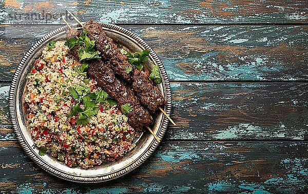 Nahöstliches türkisches Abendessen mit Fleischspieß und CouscousSalat Tabbouleh auf rustikalem Metallteller auf hölzernem Hintergrund Draufsicht mit Kopierraum  traditionelle arabische Mahlzeit