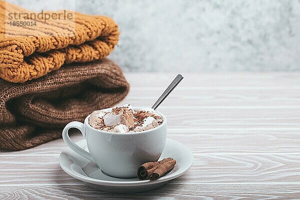 Cozy Winter Zusammensetzung  Tasse mit heißer Schokolade oder Kakao mit Marshmallow und Stapel von warmen gestrickte Kleidung auf weißem Holz rustikalen Hintergrund. Gemütliche und weiche Winter zu Hause  freier Raum für Text