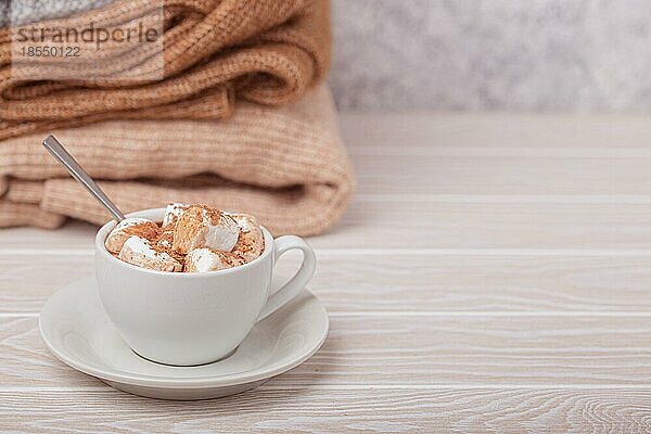 Cozy Winter Zusammensetzung  Tasse mit heißer Schokolade oder Kakao mit Marshmallow und Stapel von warmen gestrickte Kleidung auf weißem Holz rustikalen Hintergrund. Gemütliche und weiche Winter zu Hause  freier Raum für Text