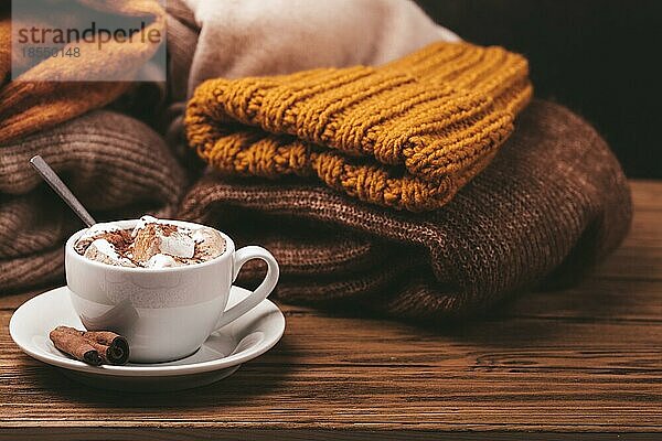 Cozy Winter Zusammensetzung  Tasse mit heißer Schokolade oder Kakao mit Marshmallow und Stapel von warmen gestrickte Kleidung auf Holz rustikalen Hintergrund. Gemütliche und weiche Winter zu Hause  freier Raum für Text