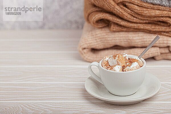 Cozy Winter Zusammensetzung  Tasse mit heißer Schokolade oder Kakao mit Marshmallow und Stapel von warmen gestrickte Kleidung auf weißem Holz rustikalen Hintergrund. Gemütliche und weiche Winter zu Hause  freier Raum für Text