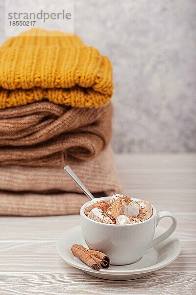 Cozy Winter Zusammensetzung  Tasse mit heißer Schokolade oder Kakao mit Marshmallow und Stapel von warmen gestrickte Kleidung auf weißem Holz rustikalen Hintergrund. Gemütliche und weiche Winter zu Hause  freier Raum für Text