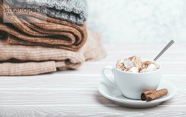 Cozy Winter Zusammensetzung  Tasse mit heißer Schokolade oder Kakao mit Marshmallow und Stapel von warmen gestrickte Kleidung auf weißem Holz rustikalen Hintergrund. Gemütliche und weiche Winter zu Hause  freier Raum für Text