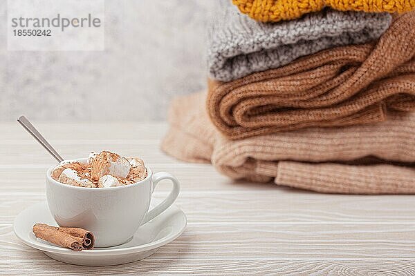 Cozy Winter Zusammensetzung  Tasse mit heißer Schokolade oder Kakao mit Marshmallow und Stapel von warmen gestrickte Kleidung auf weißem Holz rustikalen Hintergrund. Gemütliche und weiche Winter zu Hause  freier Raum für Text