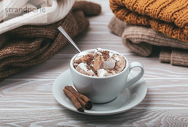 Cozy Winter Zusammensetzung  Tasse mit heißer Schokolade oder Kakao mit Marshmallow und Stapel von warmen gestrickte Kleidung auf weißem Holz rustikalen Hintergrund. Gemütliche und weiche Winter zu Hause  freier Raum für Text