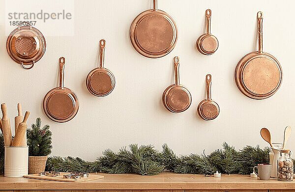 Weihnachten dekoriert Küchentheke oder Tisch in hellen modernen festlichen gemütlichen Interieur mit Backutensilien  Nudelholz  Metall Plätzchenformen  Kupfer Pfannen an der Wand  kleiner Weihnachtsbaum  Platz für Text