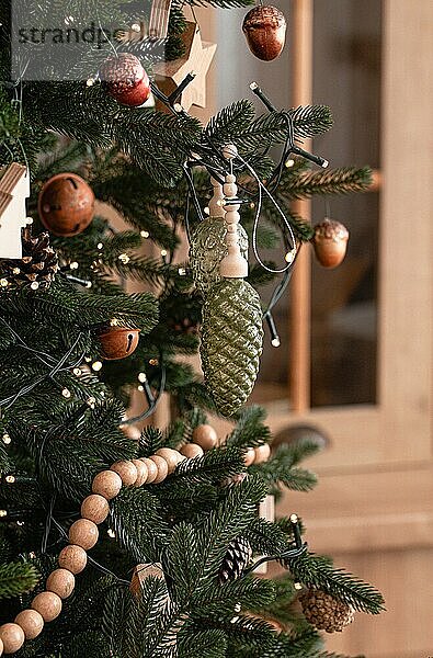 Nahaufnahme von dekoriert mit Holzspielzeug und Girlande großen schönen Weihnachtsbaum auf hellen Licht festliche moderne Küche mit Herd im skandinavischen Stil  Platz für Text