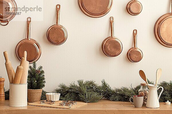 Weihnachten dekoriert Küchentheke oder Tisch in hellen modernen festlichen gemütlichen Interieur mit Backutensilien  Nudelholz  Metall Plätzchenformen  Kupfer Pfannen an der Wand  kleiner Weihnachtsbaum  Platz für Text