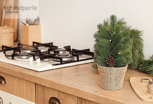 Kleiner Weihnachtsbaum und Metallplätzchenformen auf Ausstechbrett neben Küchenherd  Backen Hintergrund in hellen dekoriert festlichen Interieur  Platz für Text