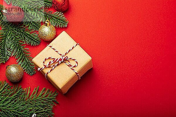 Weihnachten und Neujahr flach legen Zusammensetzung mit grünen Tannenzweig und Weihnachtsschmuck auf leuchtend roten Hintergrund und in Bastelpapier eingewickelt vorhanden Draufsicht  Platz für Text