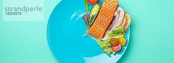 Intermittierendes Fasten niedrige Kohlenhydrate hohe Fette Diät-Konzept flach legen  gesunde Lebensmittel Lachs Fisch  Speck Fleisch  Gemüse und Salat auf blauem Teller und blauem Hintergrund von oben gesehen