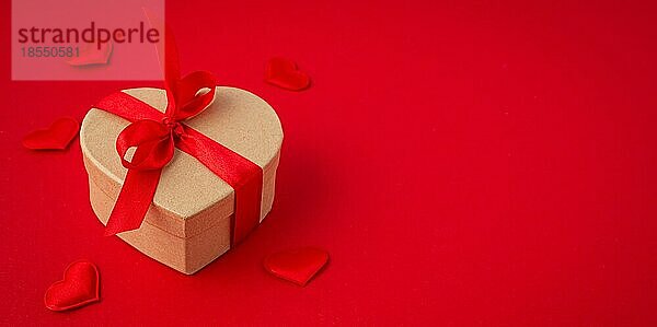 Schöne minimale verpackt Geschenk-Box herzförmig mit roter Schleife Band auf rotem Hintergrund und kleine gepolsterte Herzen Draufsicht flach legen  Geschenk für Saint Valentine Tag  Liebe und Beziehung  Platz für Text