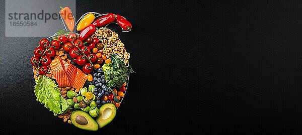 Gesunde Ernährung und Ernährung für Herz und Herz-Kreislauf-System  gesunde Lebensmittel  Obst und Gemüse Anordnung in realistischer Herzform auf schwarzer Kreidetafel Draufsicht Zusammensetzung mit Kopie Raum