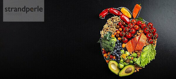 Gesunde Ernährung und Ernährung für Herz und Herz-Kreislauf-System  gesunde Lebensmittel  Obst und Gemüse Anordnung in realistischer Herzform auf schwarzer Kreidetafel Draufsicht Zusammensetzung mit Kopie Raum